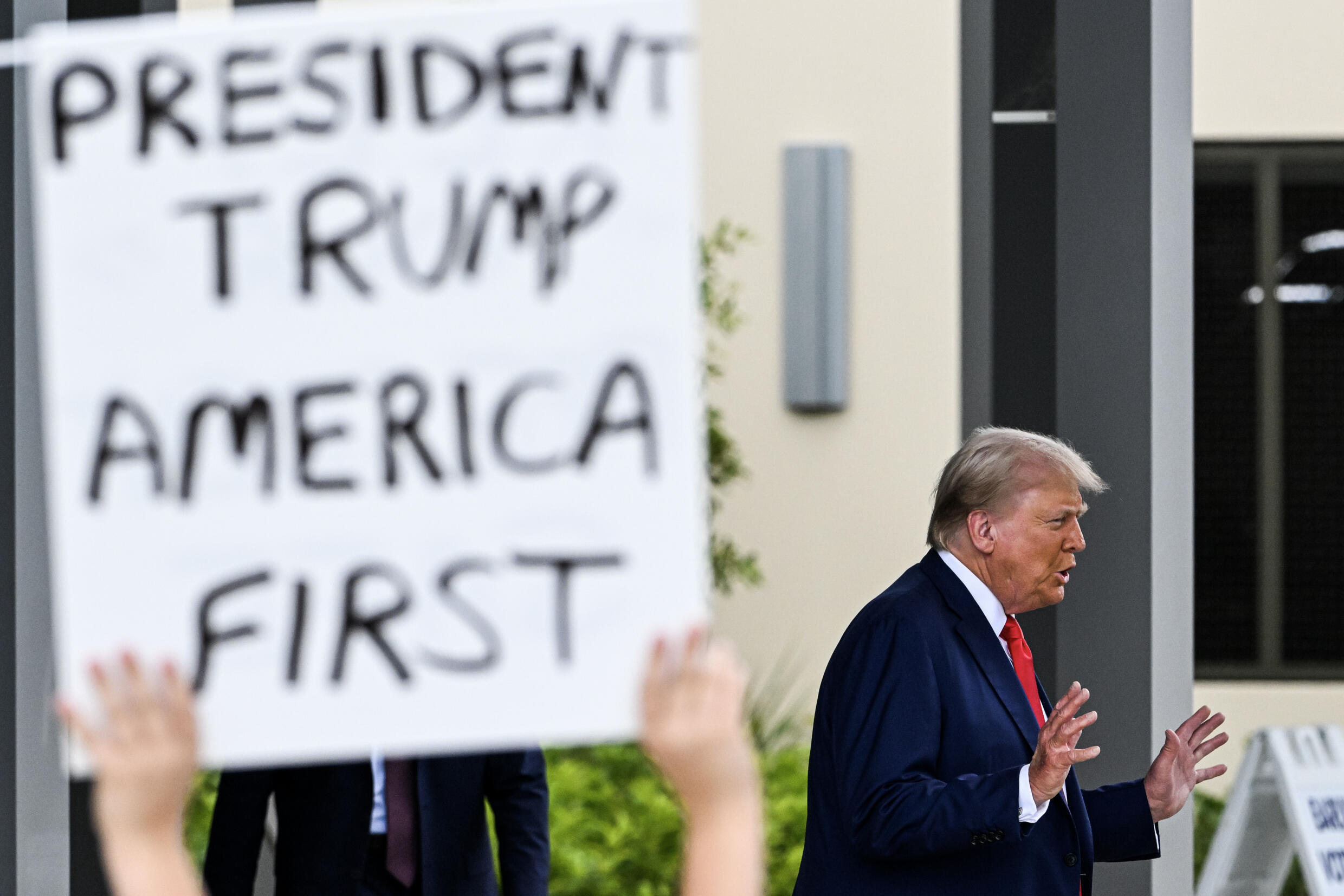 A supporter holds up a sign as former US President and Republican presidential candidate Donald Trump leaves after casting his vote in Florida's primary election on August 14, 2024 in West Palm Beach.